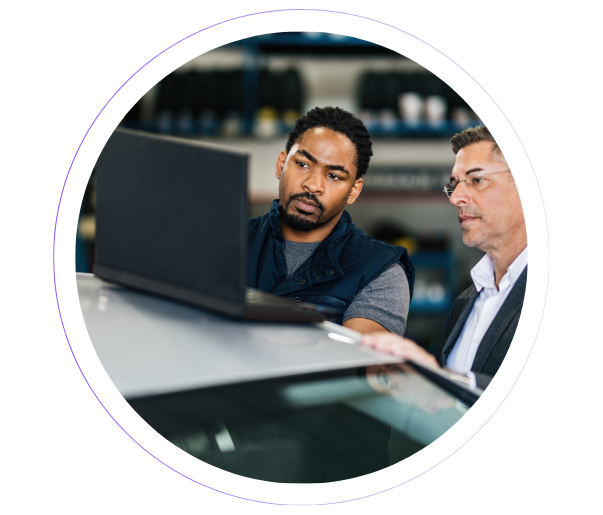 Two manufacturing professionals reviewing data on a laptop, representing real-time SAP integration and system uptime.